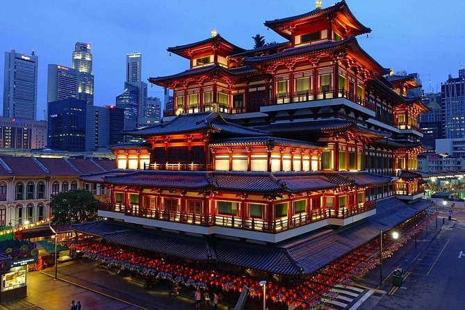 The Buddha Tooth Relic Temple in Chinatown lit red at blue hour, with the office towers behind it