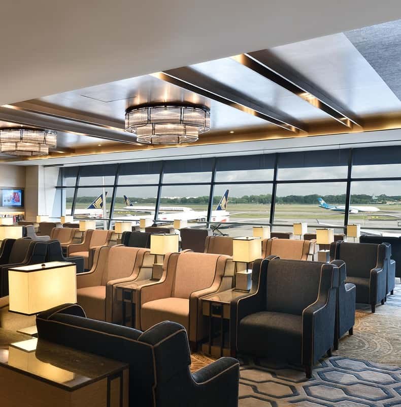 Armchairs and low tables in a Changi Airport lounge, with the runway through the window