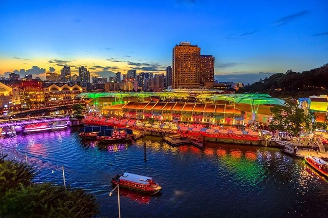 Clarke Quay lit along the Singapore River at dusk, with bumboats moored at the bank