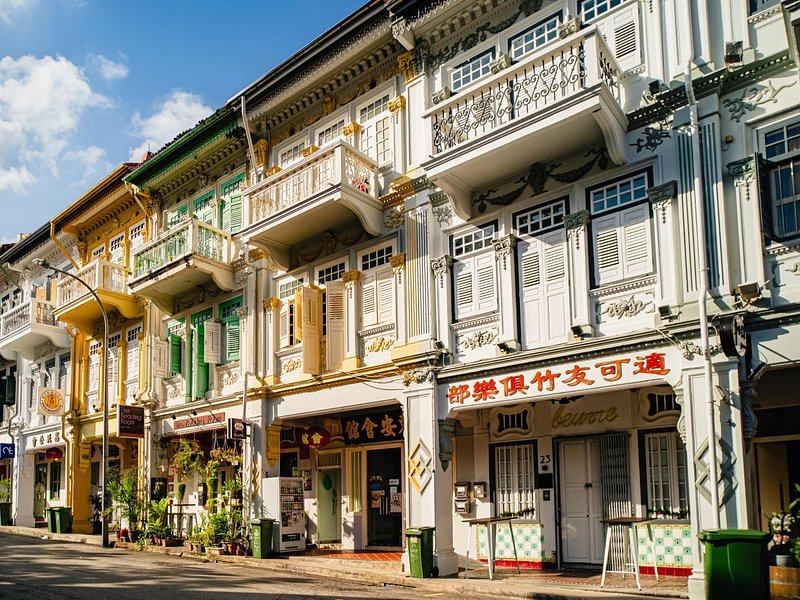 A terrace of shophouses in cream, green and ochre along a quiet Singapore street
