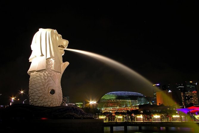 The Merlion statue spouting water into Marina Bay at night