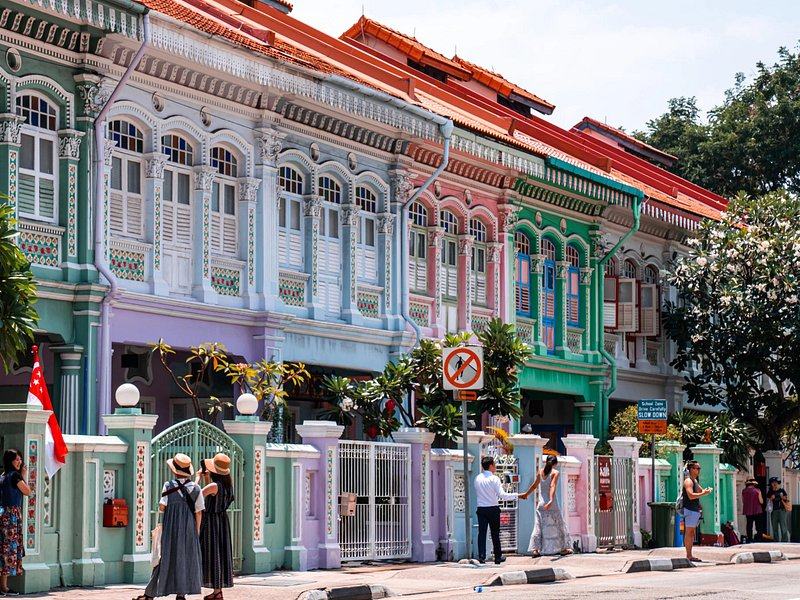 Pastel Peranakan shophouses with shuttered upper windows and a five-foot-way beneath