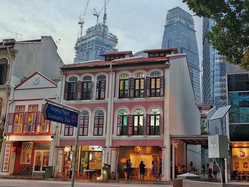 Restored two-storey shophouses standing directly beneath the glass towers of the financial district